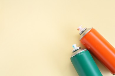 Spray paint cans on beige background, top view. Space for text