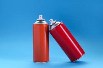 Photo of Two spray paint cans on light blue background