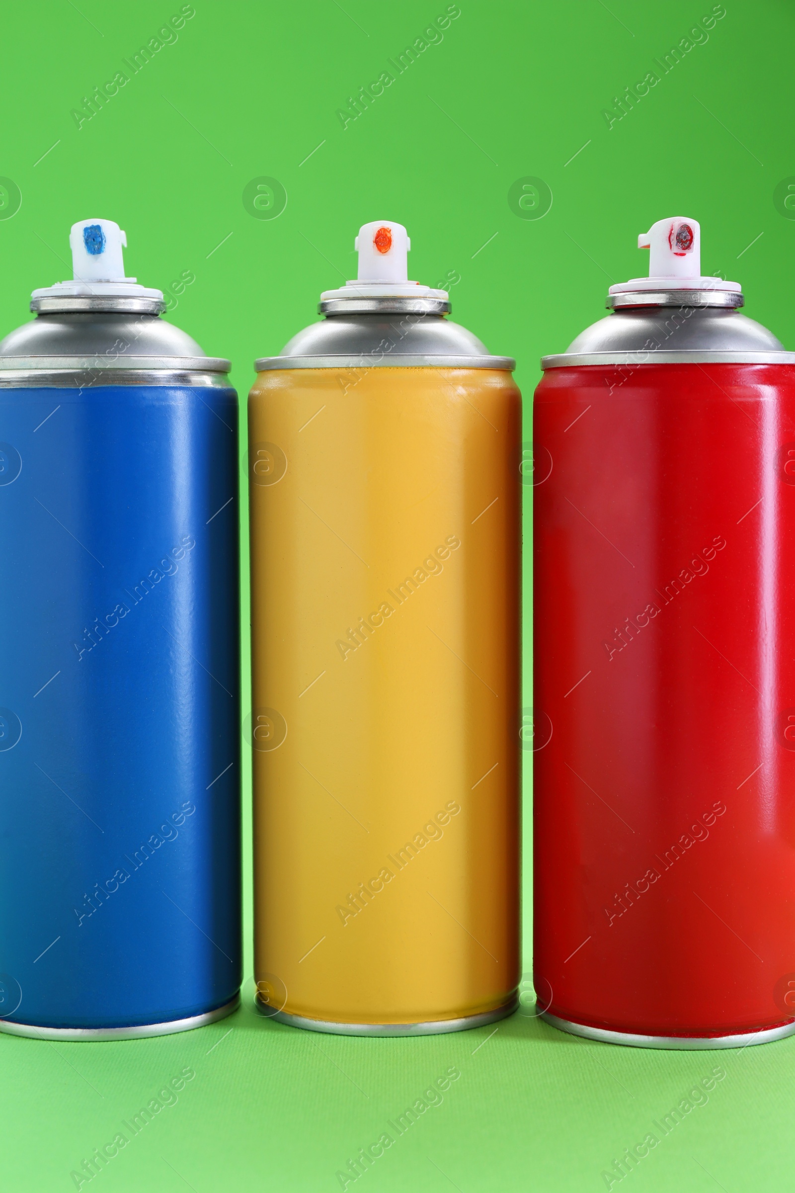 Photo of Many spray paint cans on green background