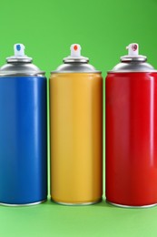 Many spray paint cans on green background