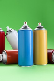 Photo of Many spray paint cans on green background