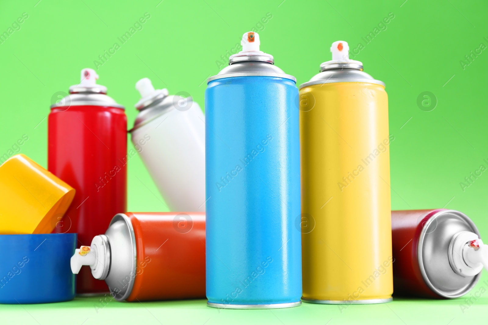 Photo of Many spray paint cans on green background, closeup