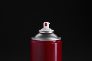 Red spray paint can on black background, closeup