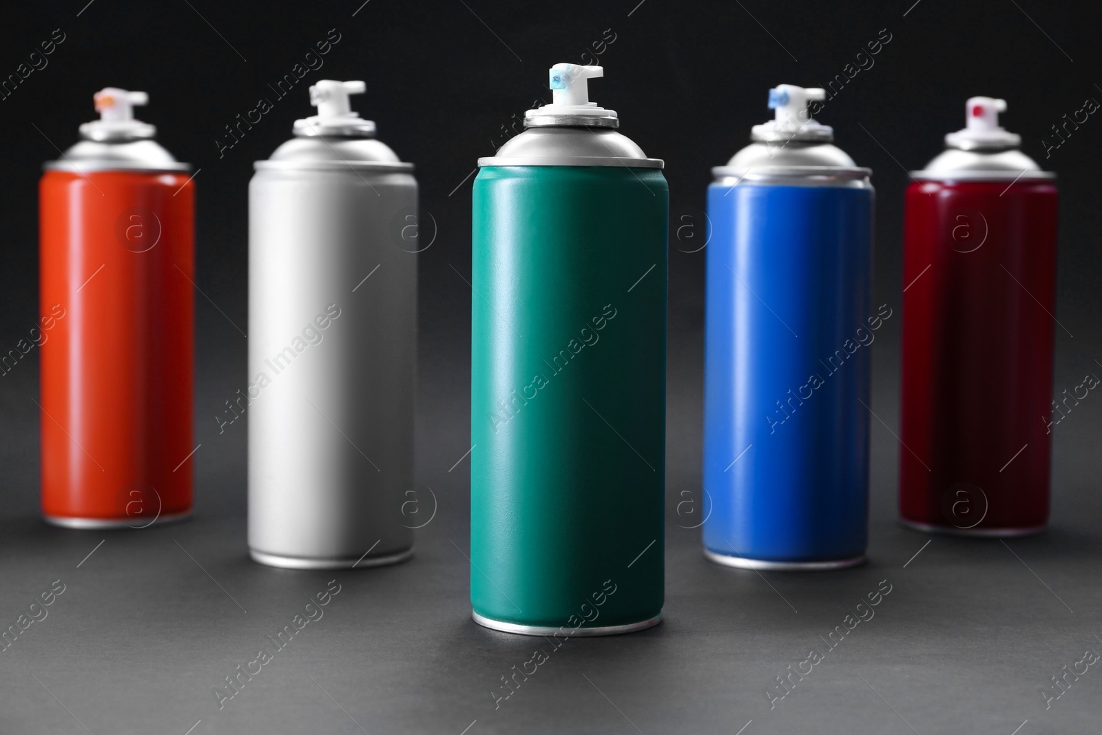 Photo of Many spray paint cans on dark gray background