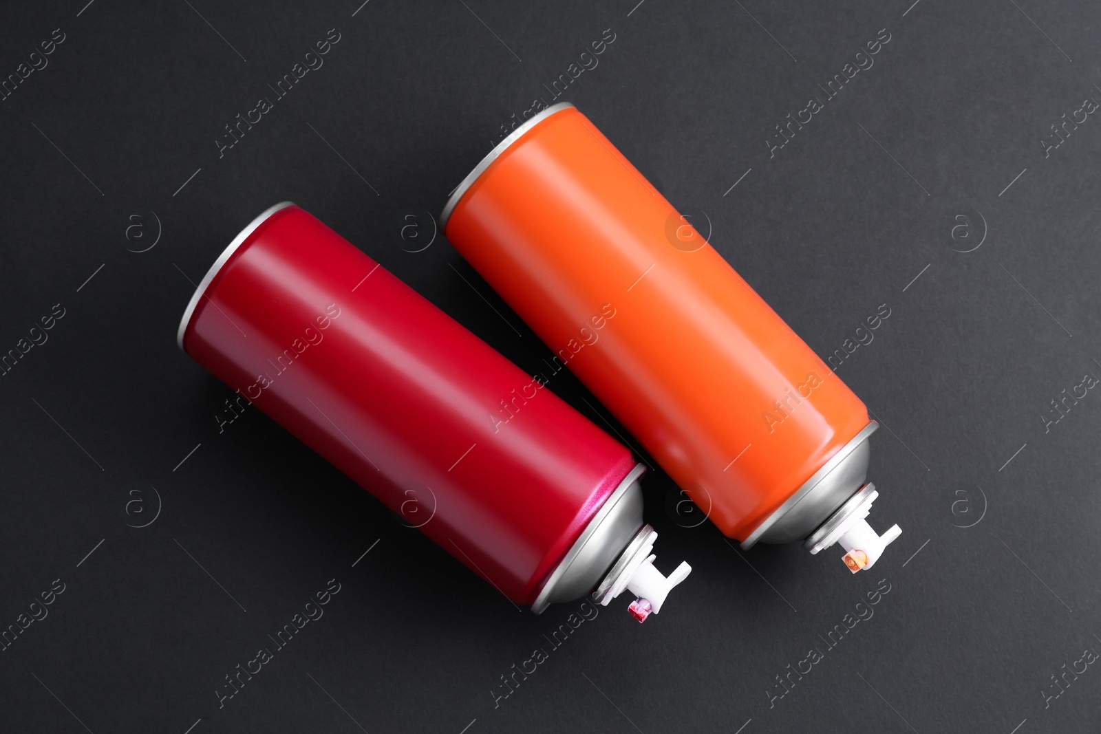 Photo of Two spray paint cans on dark gray background, top view