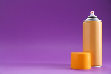 Photo of Orange spray paint can on violet background, space for text