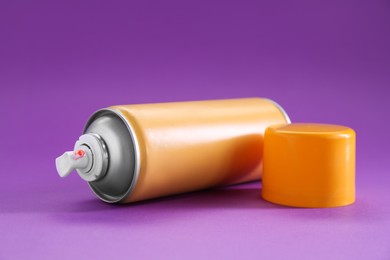 Photo of Orange spray paint can on violet background