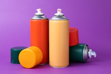 Many spray paint cans on violet background