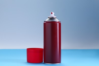 Red spray paint can on color background