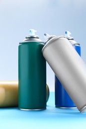 Photo of Many spray paint cans on color background