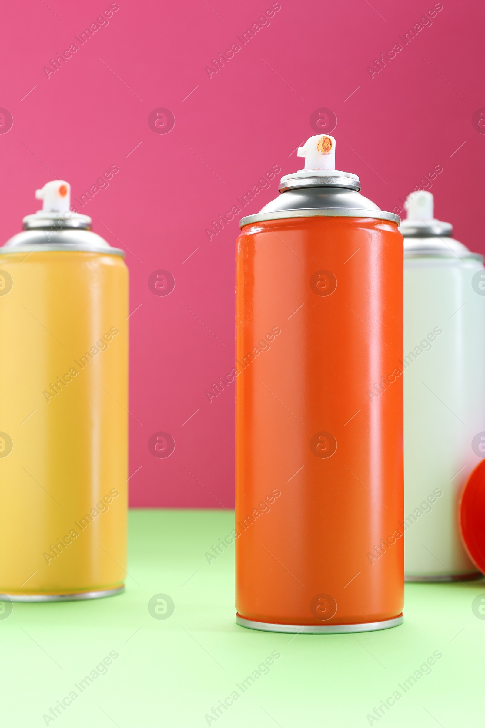 Photo of Many spray paint cans on color background