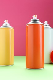 Many spray paint cans on color background