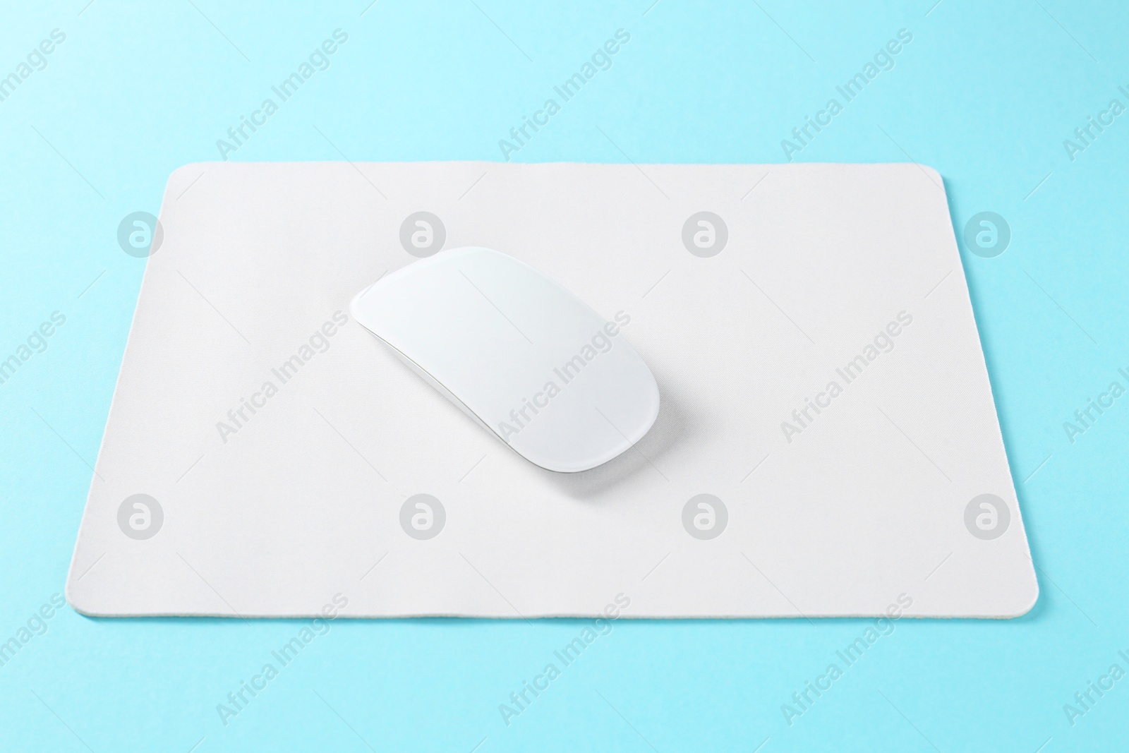 Photo of Wireless mouse and mousepad on light blue background