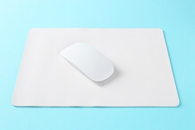 Photo of Wireless mouse and mousepad on light blue background