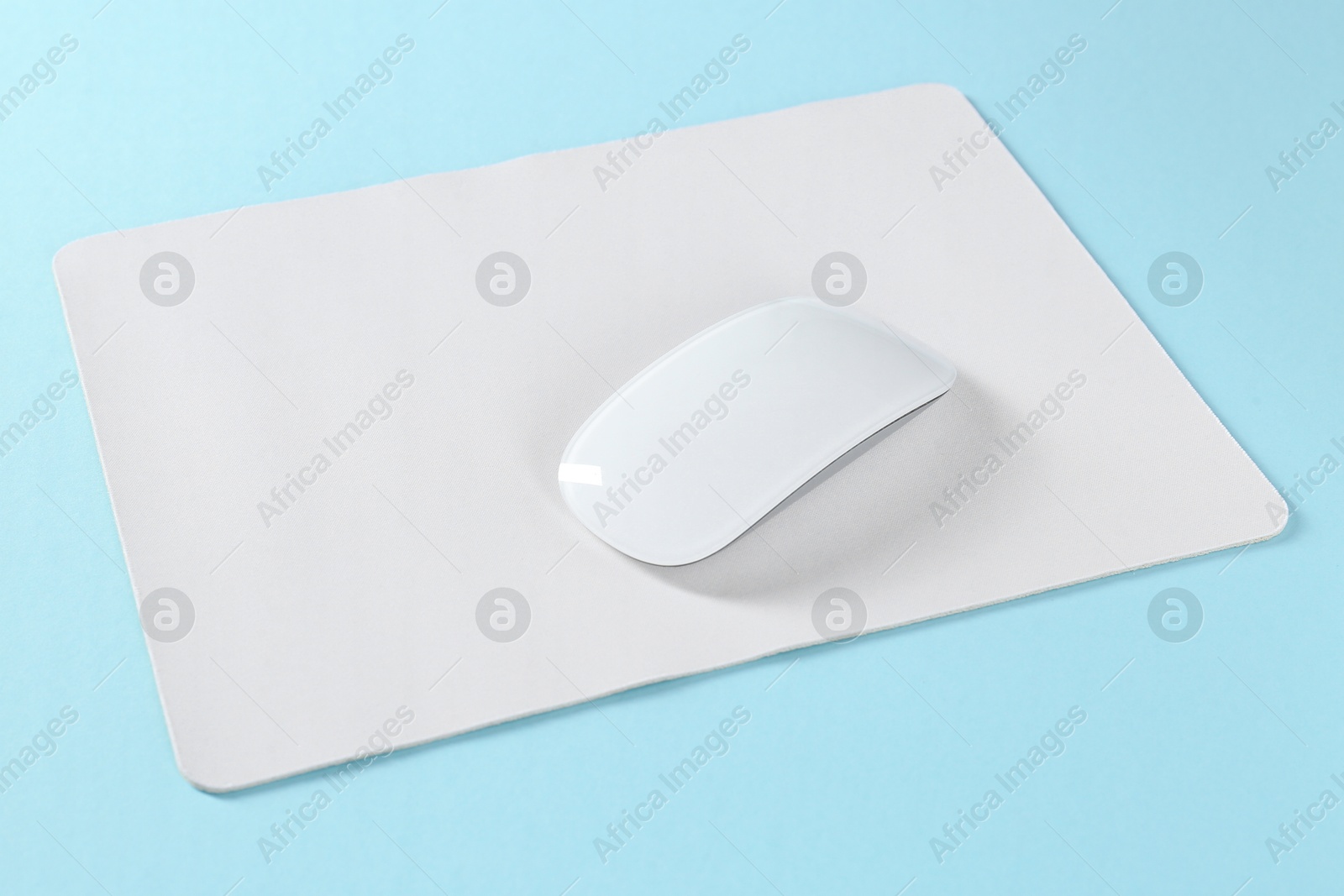 Photo of Wireless mouse and mousepad on light blue background