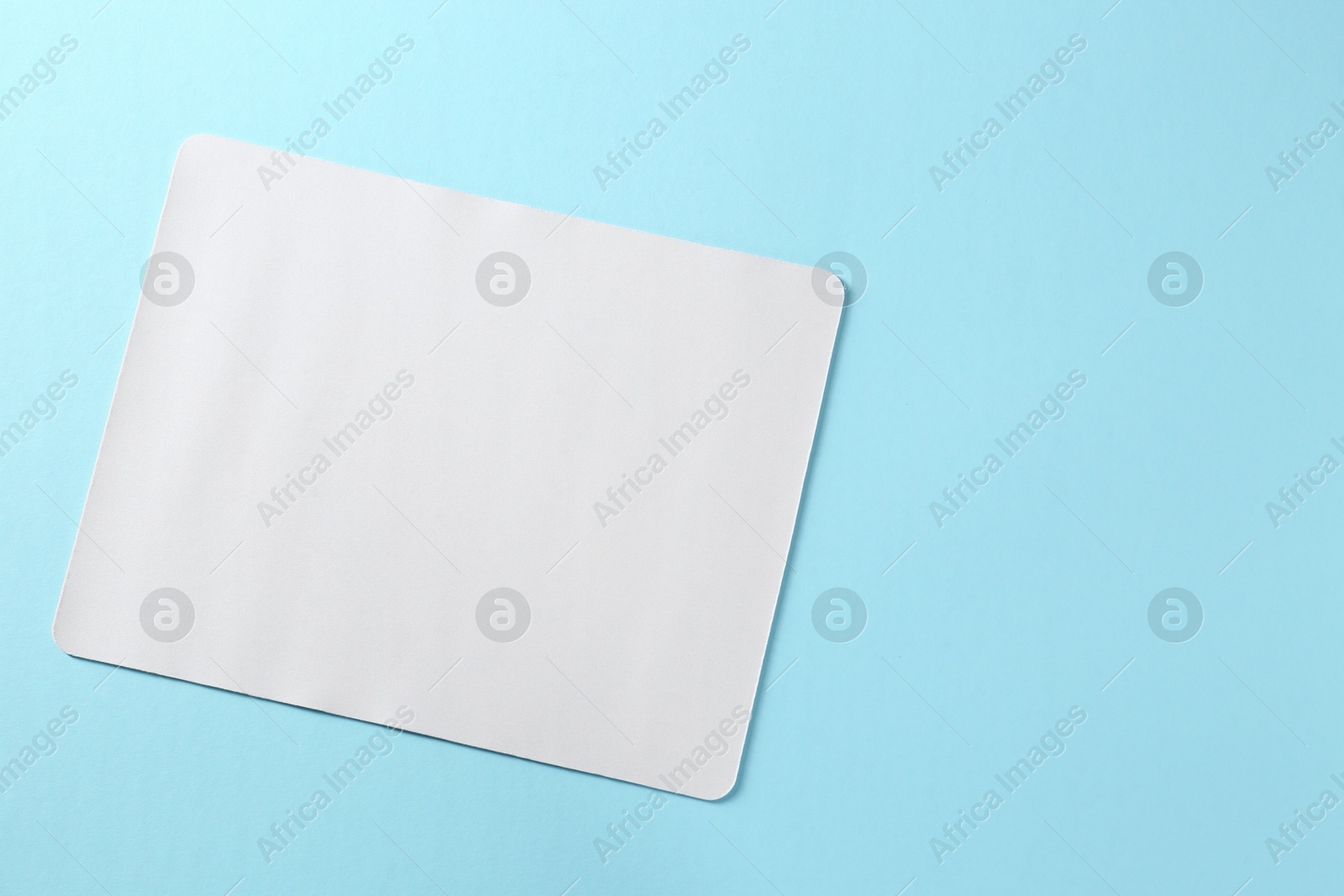 Photo of One mouse pad on light blue background, top view. Space for text