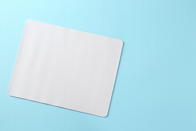 One mouse pad on light blue background, top view. Space for text