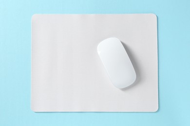 Photo of Wireless mouse and mousepad on light blue background, top view