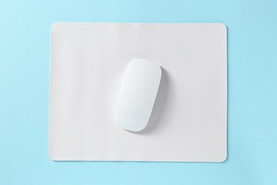 Photo of Wireless mouse and mousepad on light blue background, top view