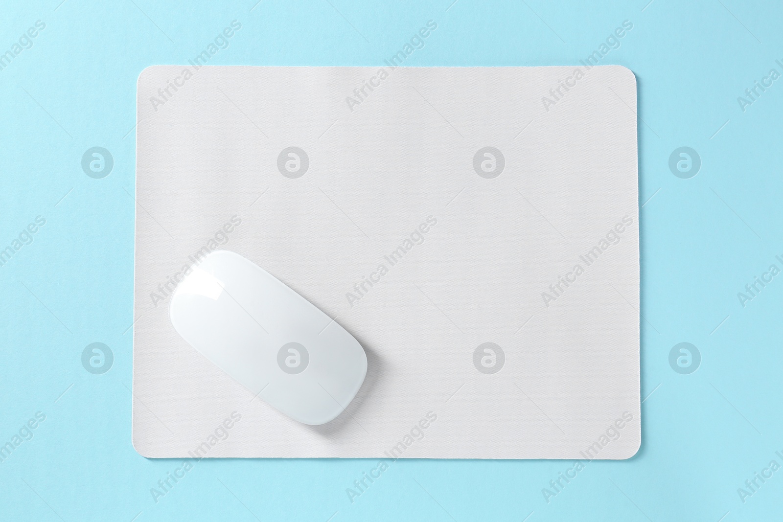 Photo of Wireless mouse and mousepad on light blue background, top view