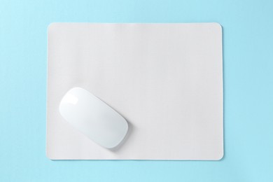 Photo of Wireless mouse and mousepad on light blue background, top view