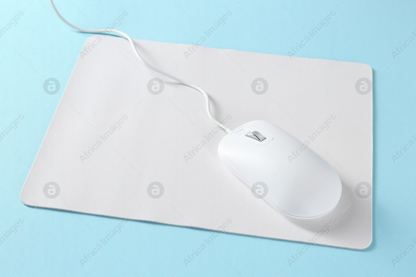 Photo of Wired mouse and mousepad on light blue background