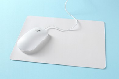 Photo of Wired mouse and mousepad on light blue background