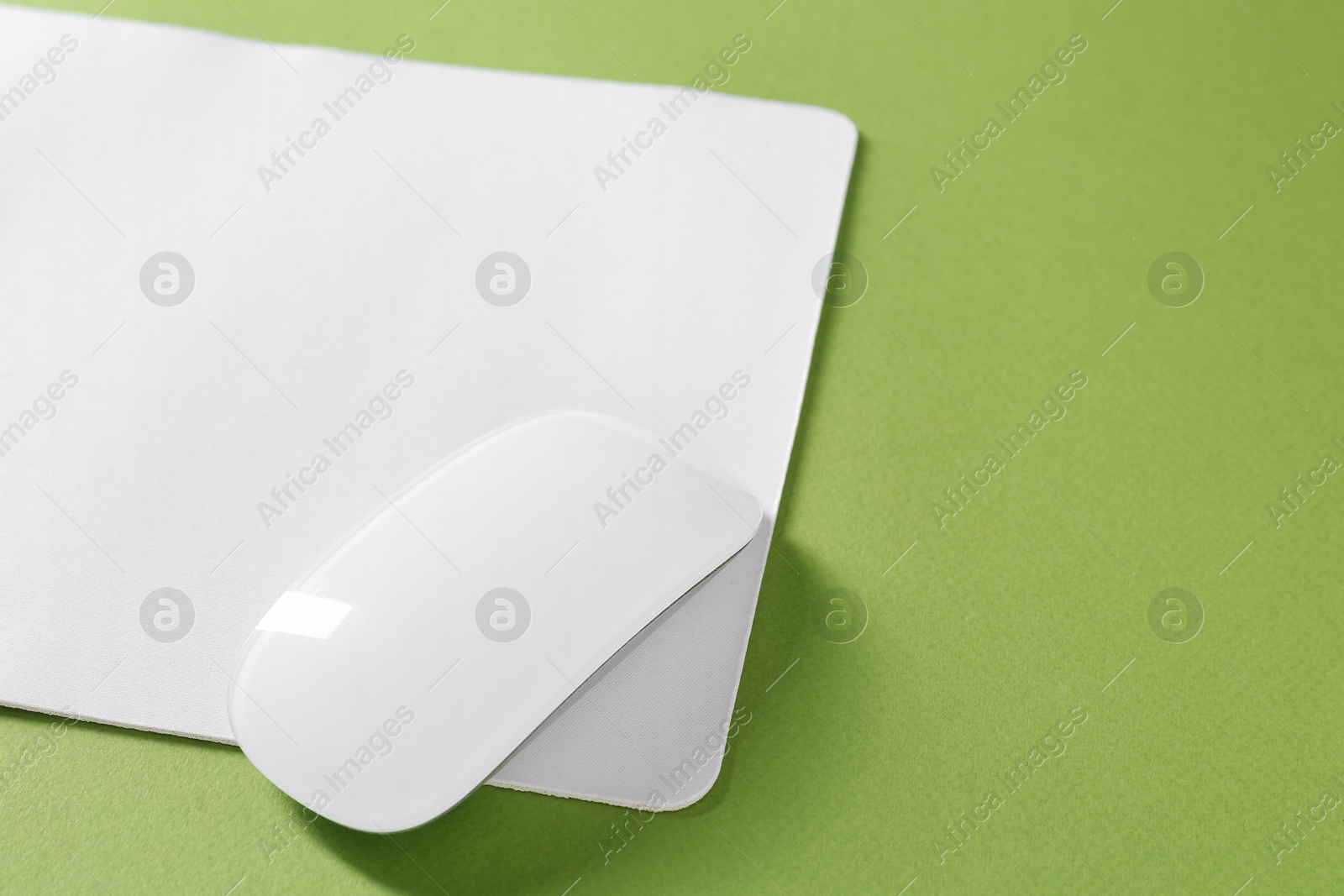 Photo of Wireless mouse and mousepad on green background, space for text