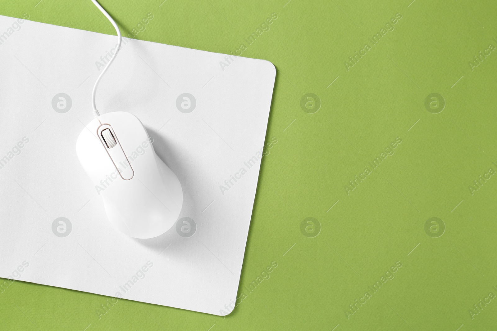 Photo of Wired mouse and mousepad on green background, top view. Space for text