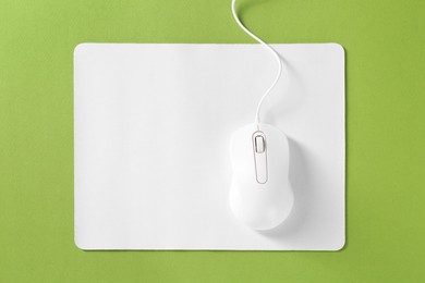 Wired mouse and mousepad on green background, top view