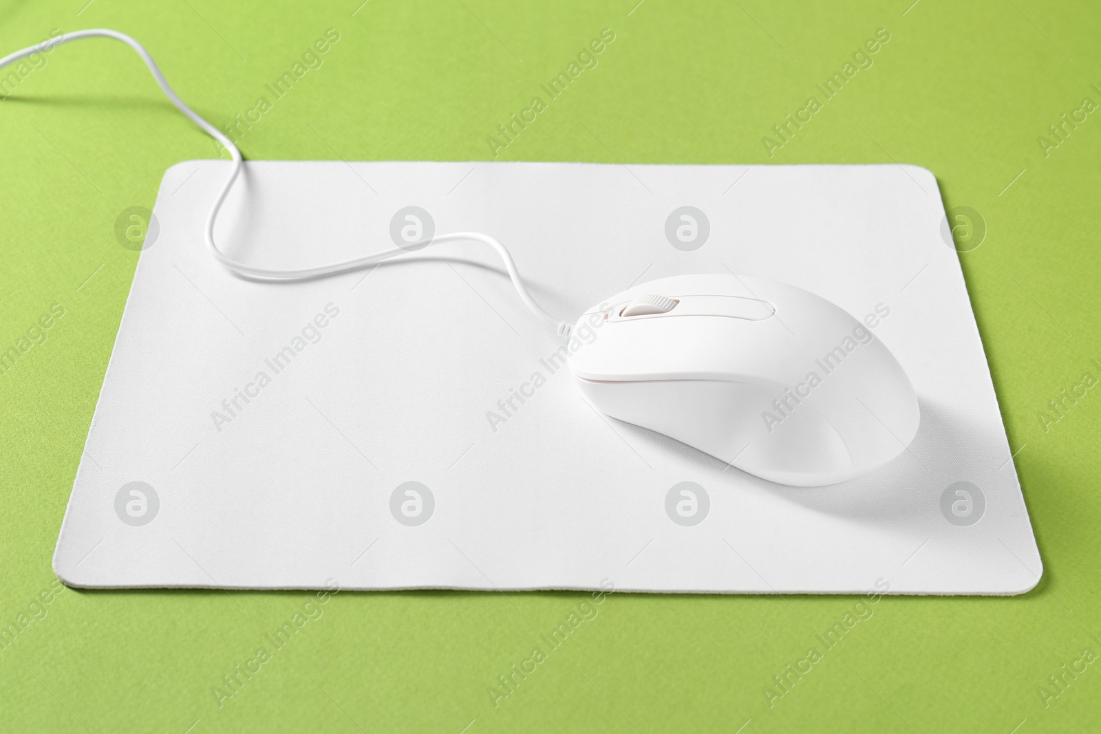 Photo of Wired mouse and mousepad on green background