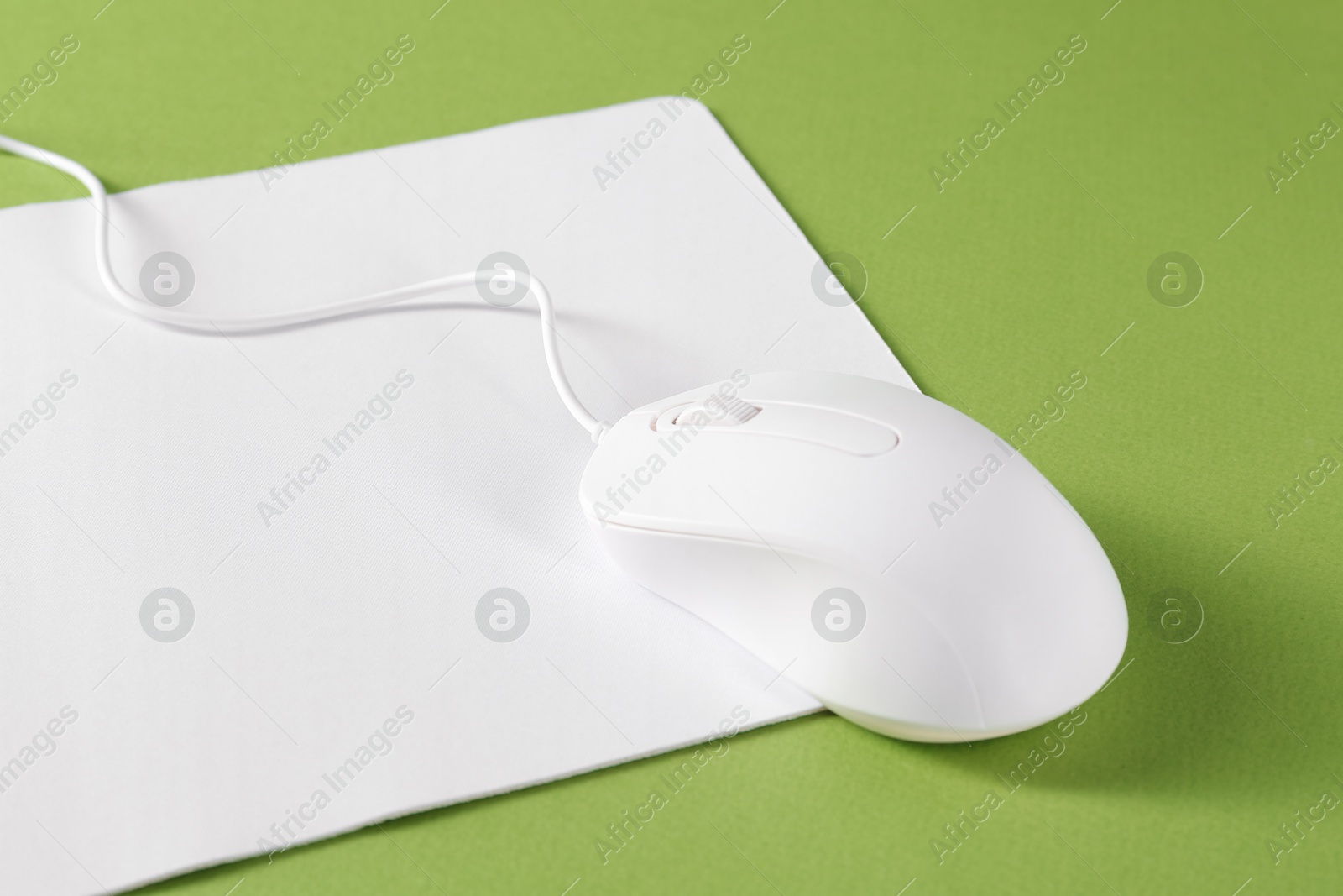 Photo of Wired mouse and mousepad on green background