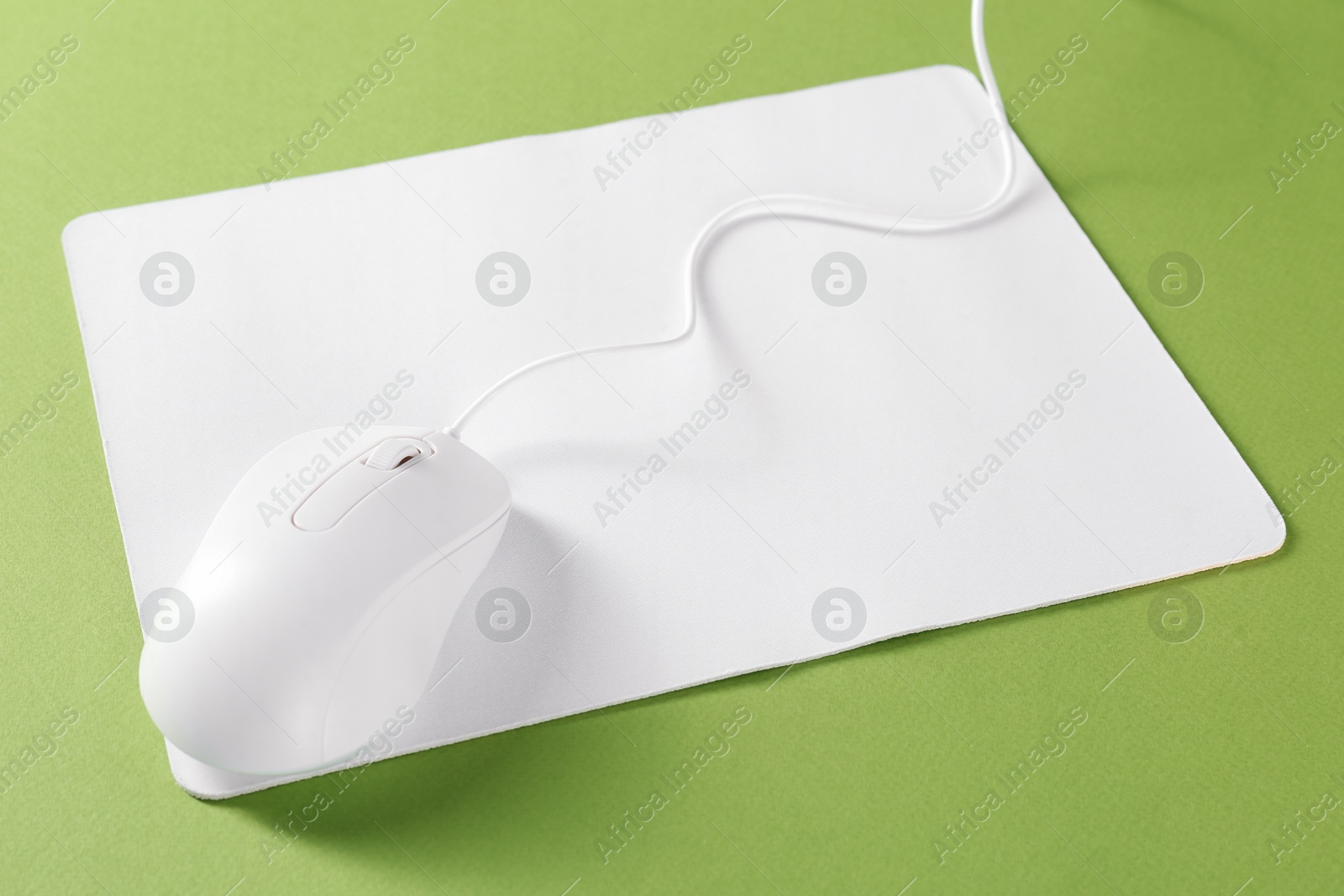 Photo of Wired mouse and mousepad on green background