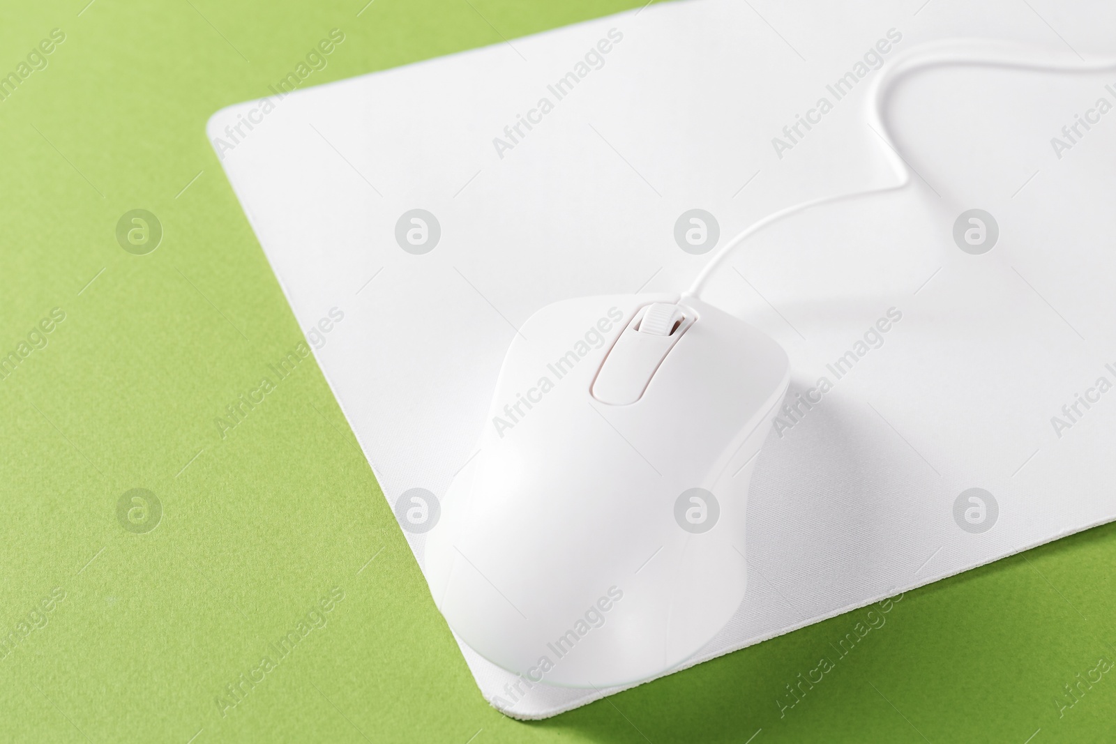 Photo of Wired mouse and mousepad on green background, closeup