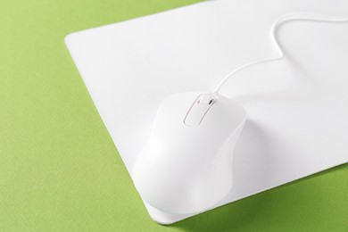 Wired mouse and mousepad on green background, closeup