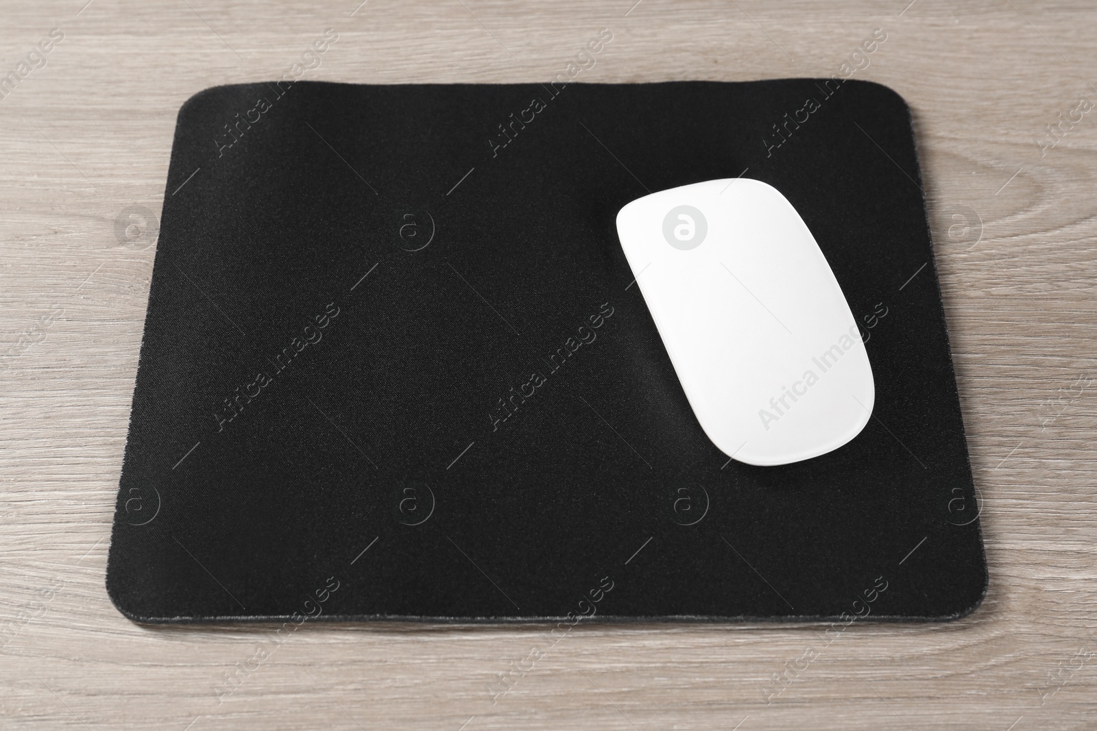 Photo of Wireless mouse and mousepad on wooden table