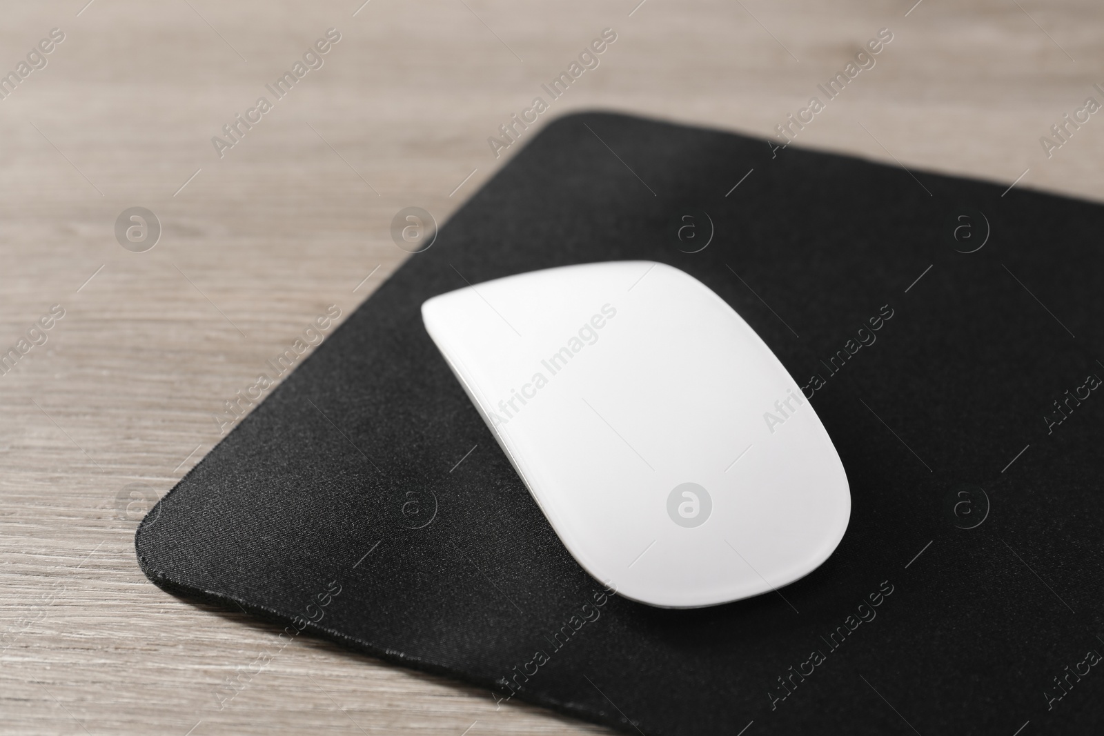 Photo of Wireless mouse and mousepad on wooden table