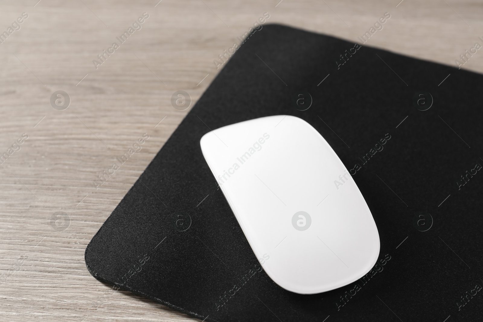 Photo of Wireless mouse and mousepad on wooden table