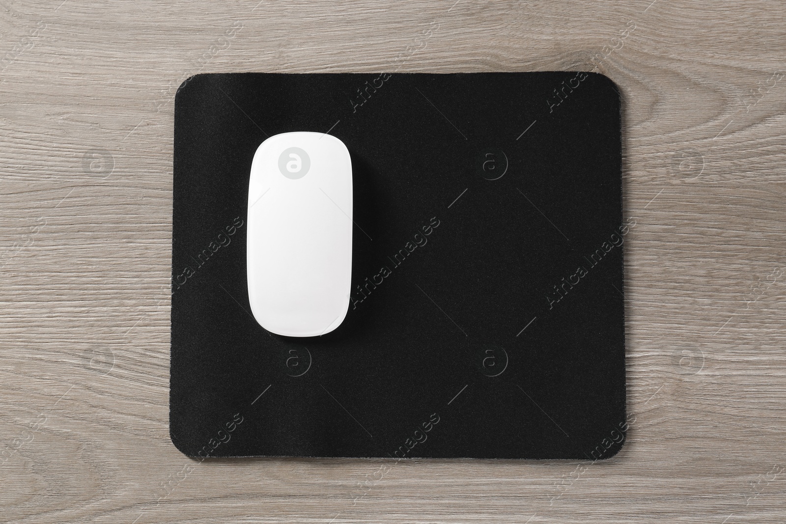 Photo of Wireless mouse and mousepad on wooden table, top view