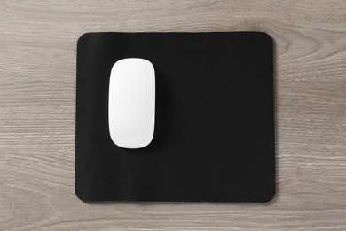 Wireless mouse and mousepad on wooden table, top view