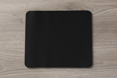 Photo of One black mouse pad on wooden table, top view