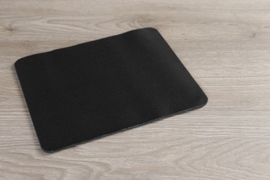 One black mouse pad on wooden table