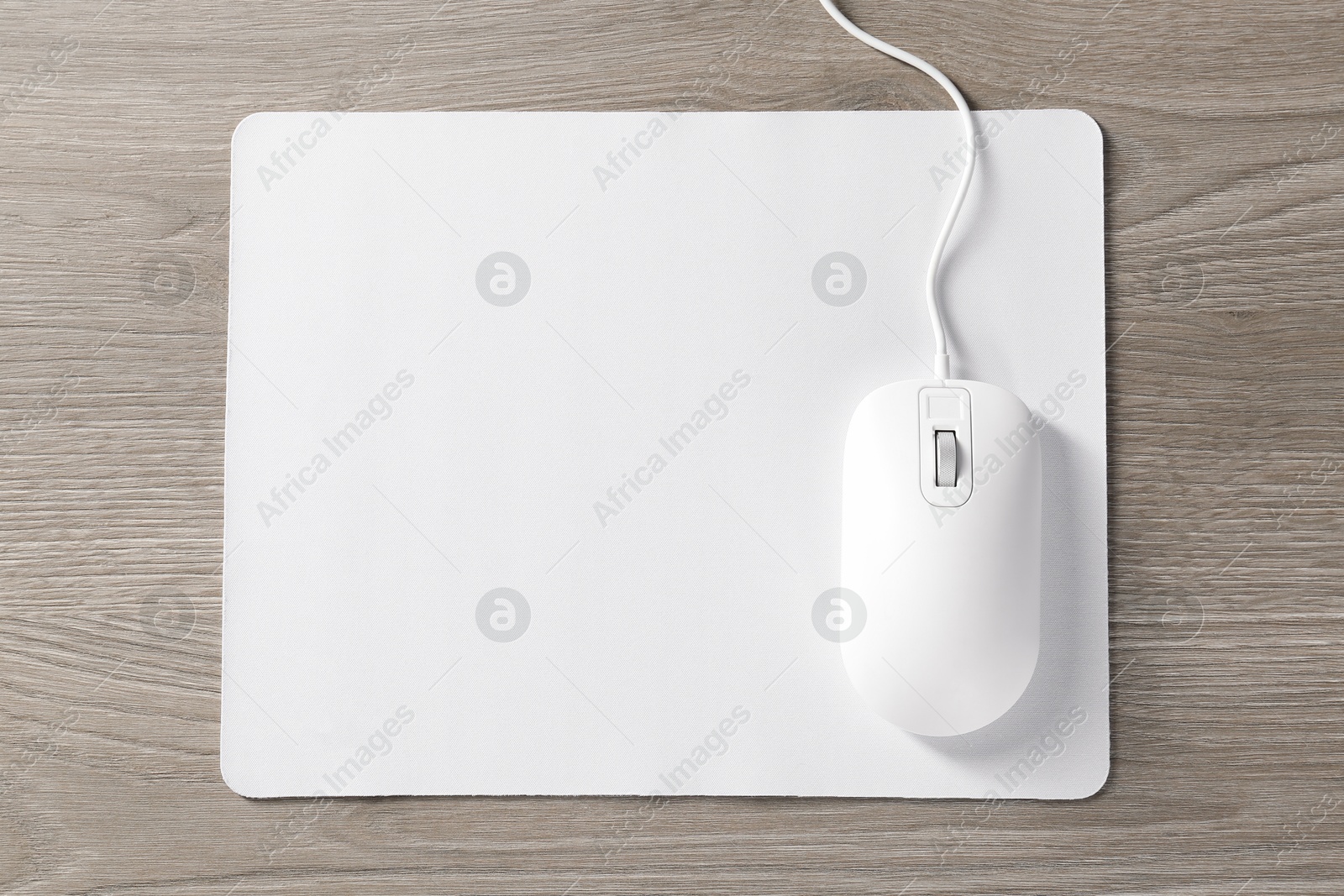 Photo of Wired mouse and mousepad on wooden table, top view