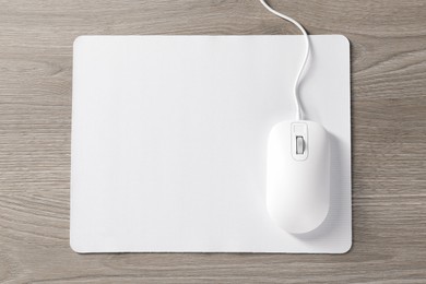 Photo of Wired mouse and mousepad on wooden table, top view