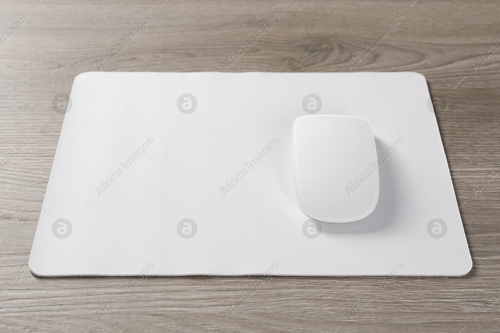 Photo of Wireless mouse and mousepad on wooden table