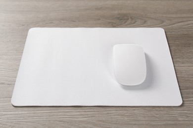 Photo of Wireless mouse and mousepad on wooden table