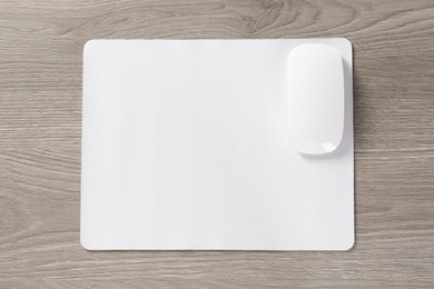 Photo of Wireless mouse and mousepad on wooden table, top view