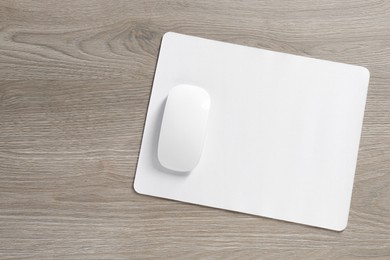 Photo of Wireless mouse and mousepad on wooden table, top view. Space for text