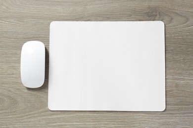 Photo of Wireless mouse and mousepad on wooden table, top view