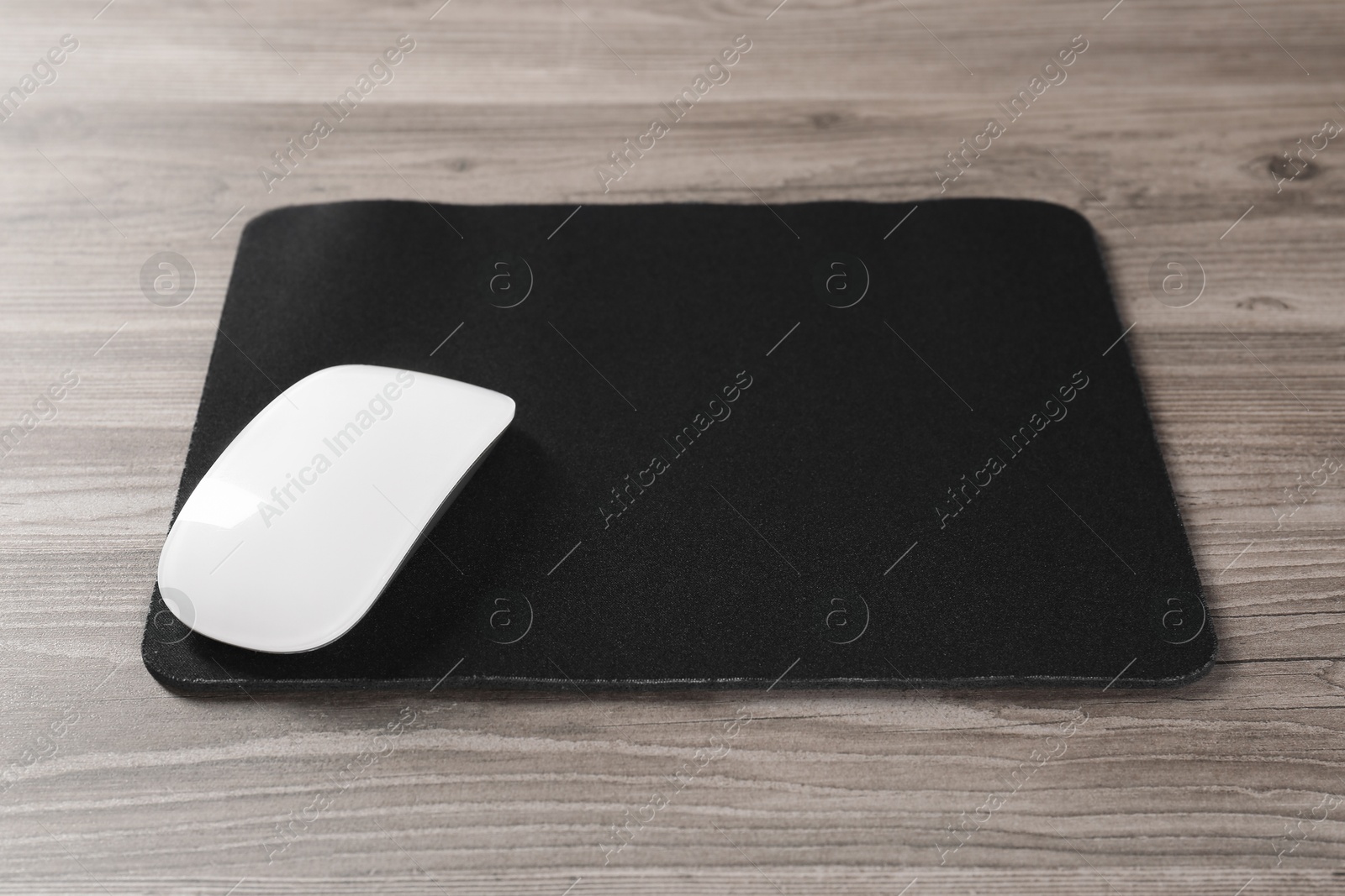 Photo of Wireless mouse and mousepad on wooden table